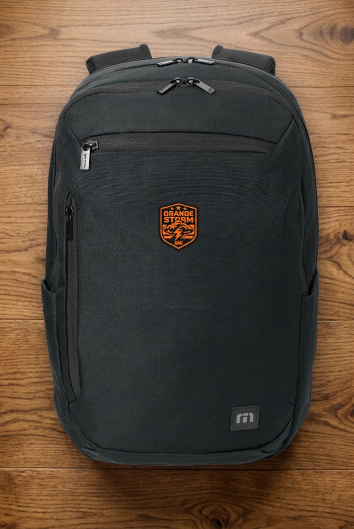 Black TravisMathew backpack with an orange custom team patch