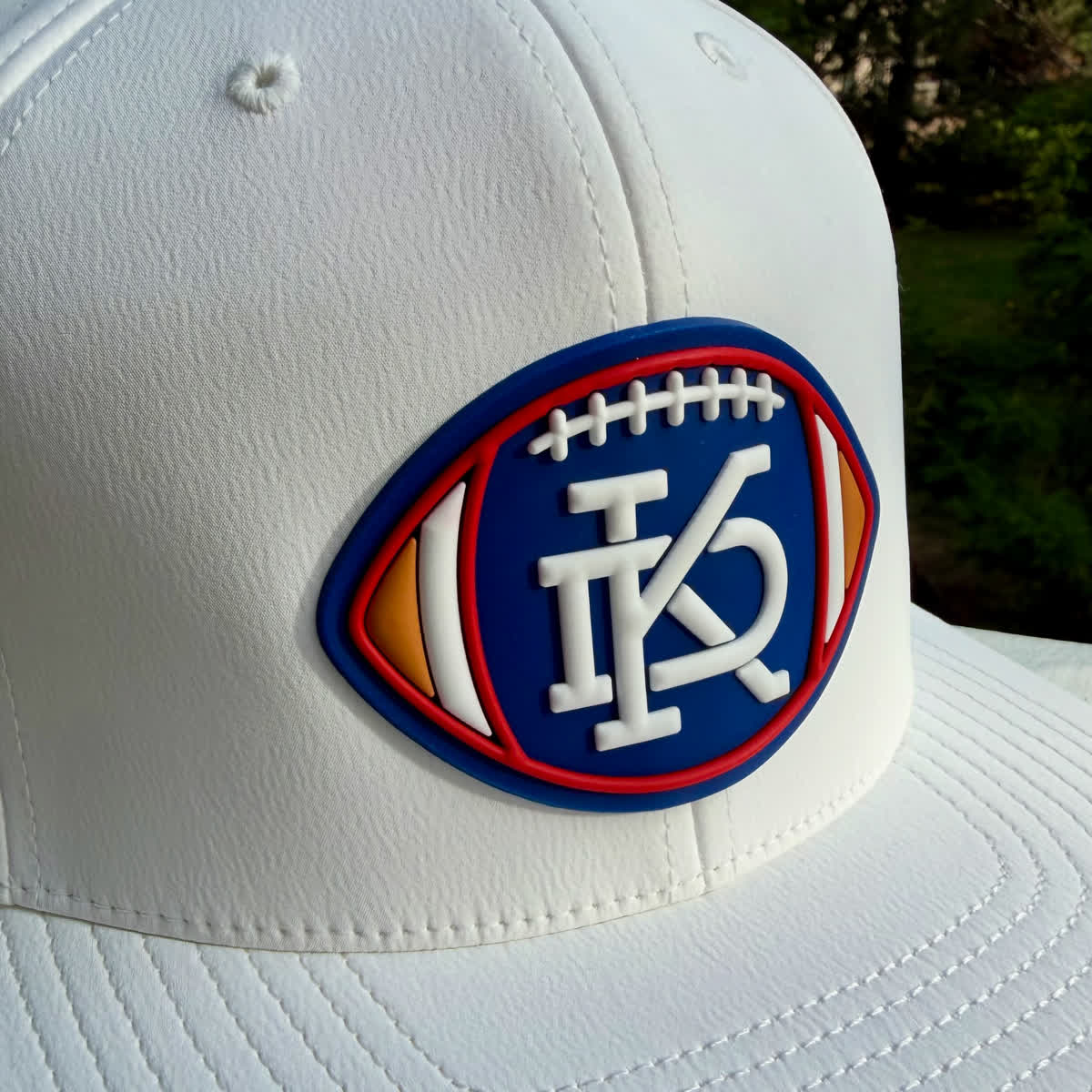 White Branded Bills hat with a raised PVC football patch in navy, red, orange, and white