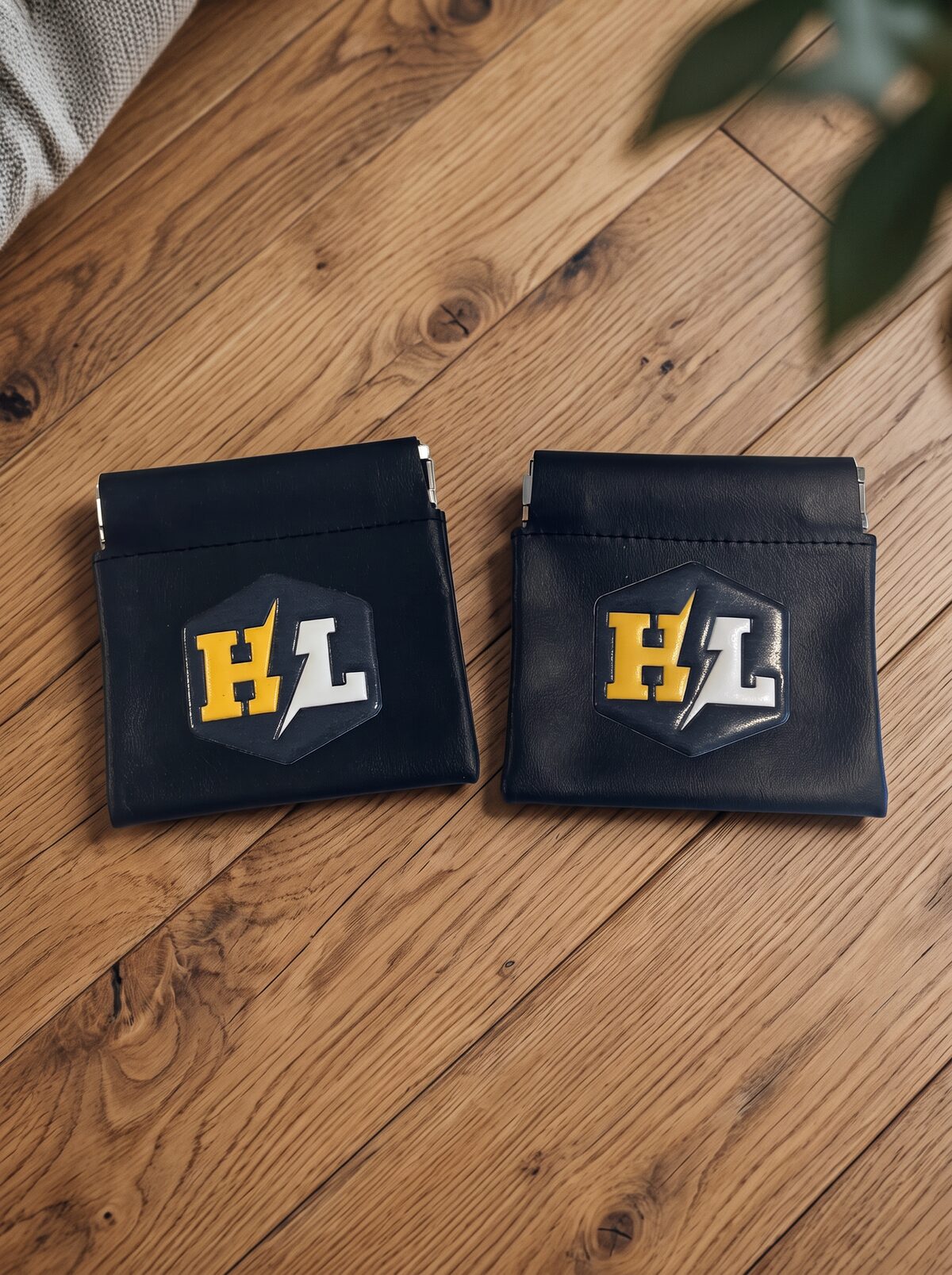 Two black leather snap pouches with custom raised logo patches