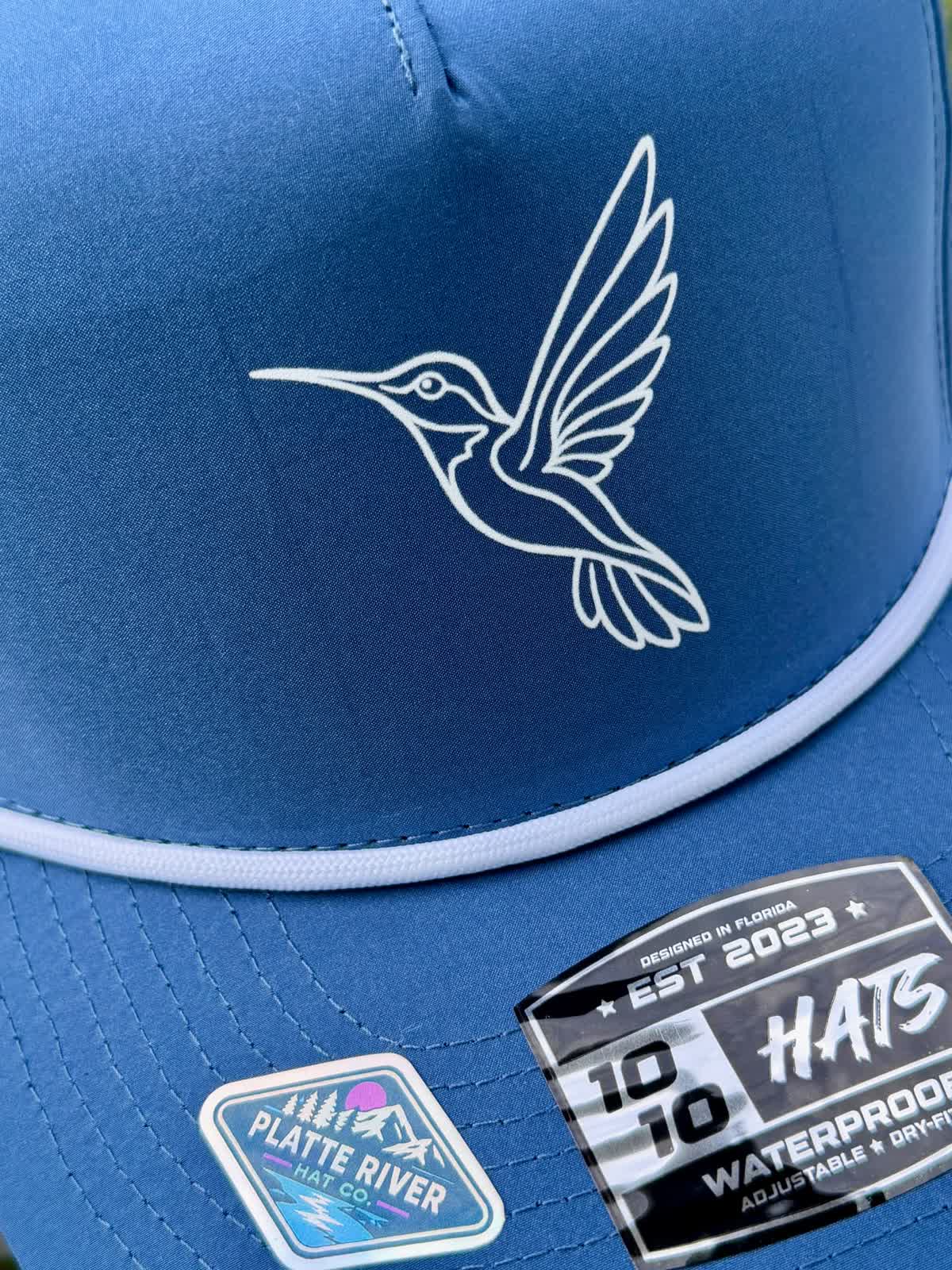 Blue 10-10 rope hat with a white fine-line DTF hummingbird