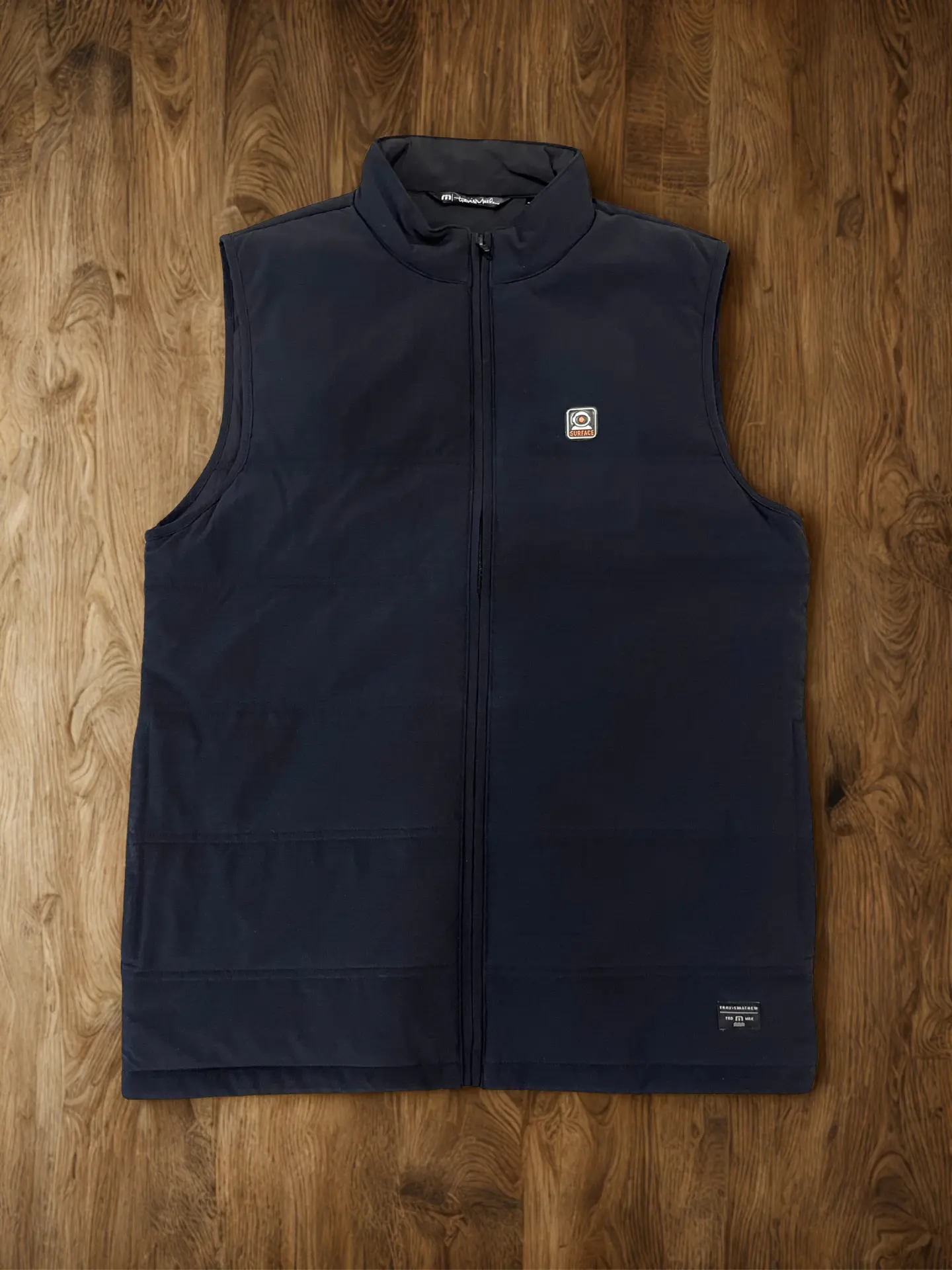 Navy TravisMathew vest with a custom woven patch on the chest